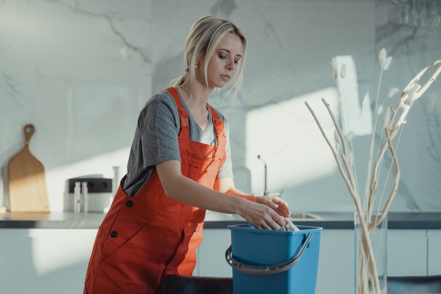 Cleaner in work overalls preparing cleaning supplies